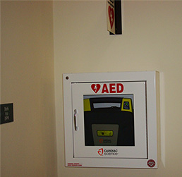 Photo of an AED machine in a secured box on the wall of a building